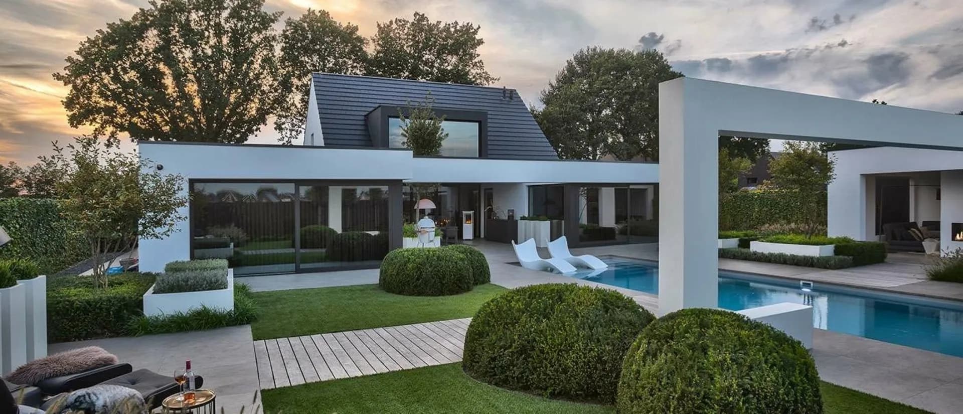 Strak gemaaid gazon langs een zwembad in een luxe tuin in het Gooi